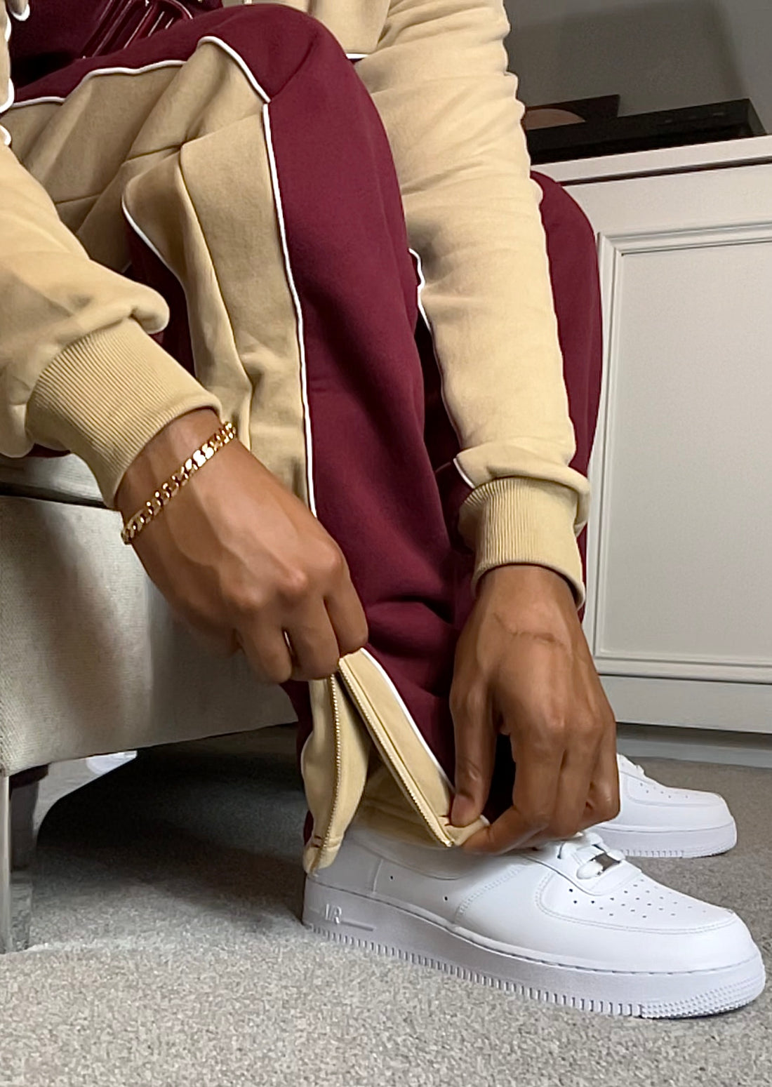 Man showing gold detailing of heavyweight Burgundy and cream joggers