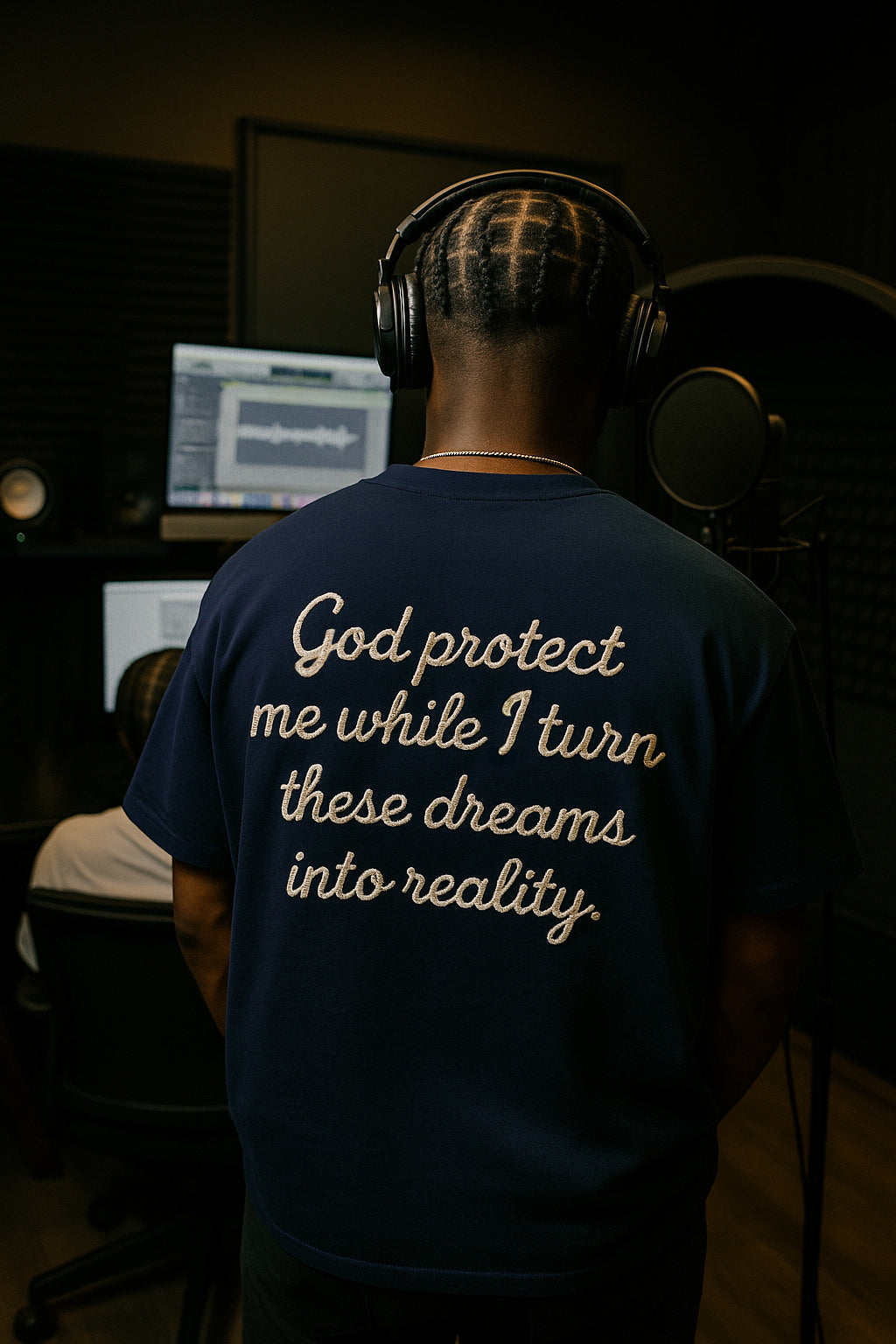 Person wearing a blue t-shirt with a motivational quote in a recording studio.