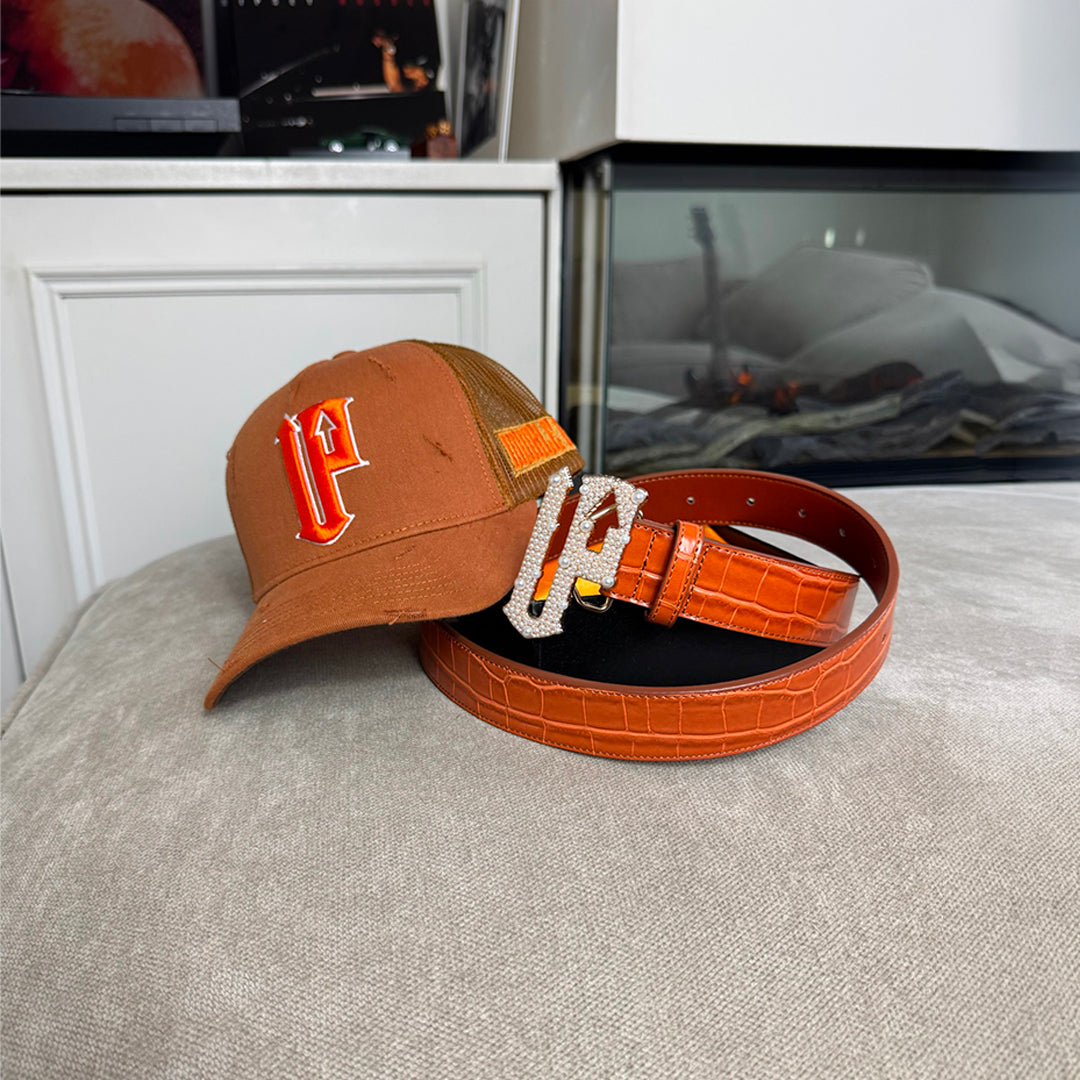 Orange cap and belt with decorative buckle on a textured surface