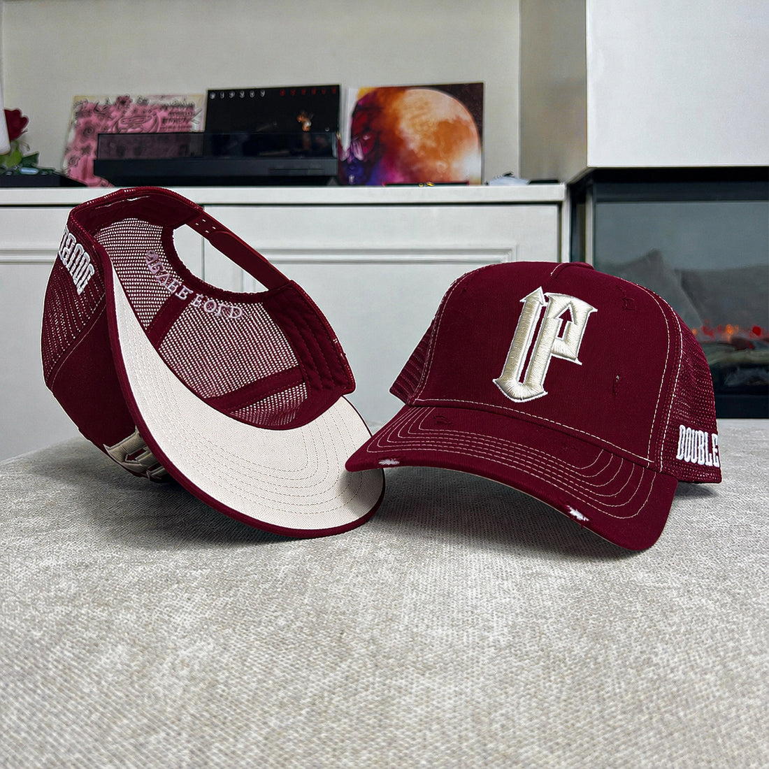 Two maroon and white caps with a logo on a gray surface.