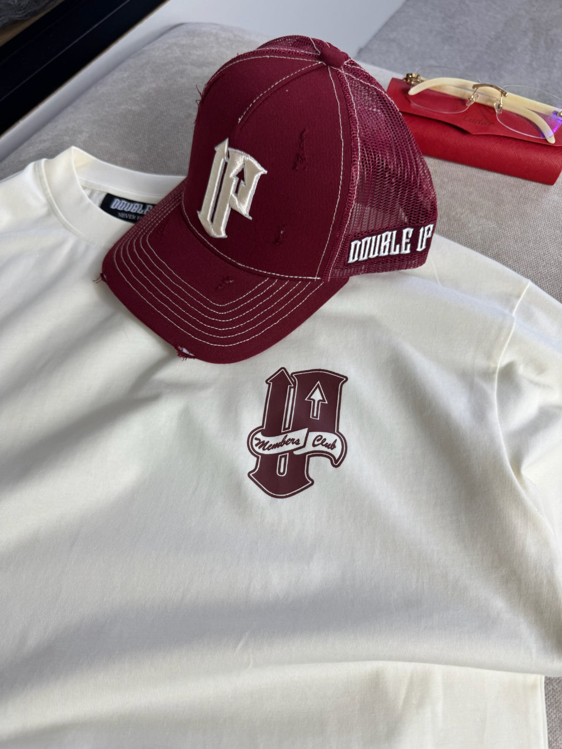 White shirt with maroon cap featuring a logo on a gray surface