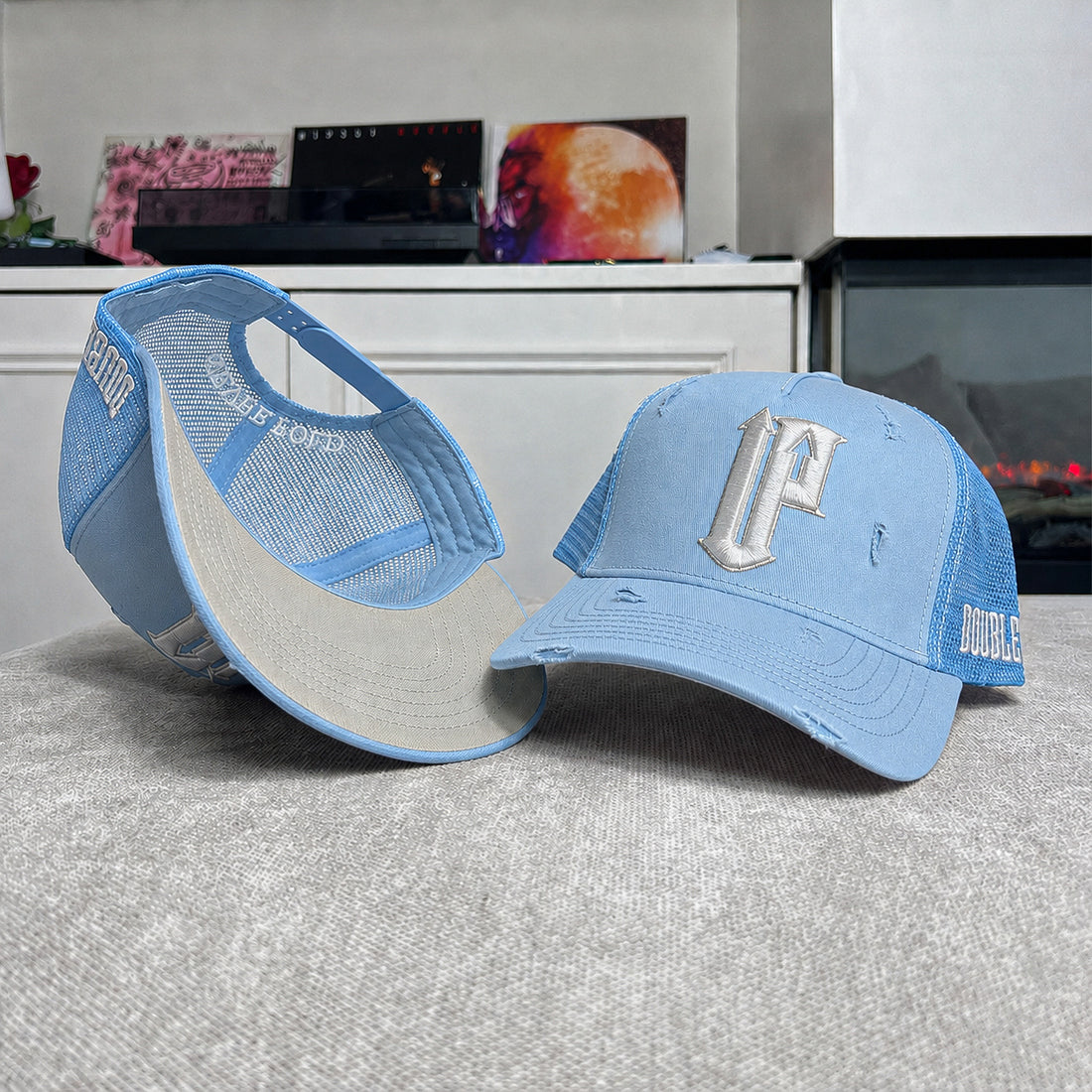 Two blue caps with branding on a textured surface